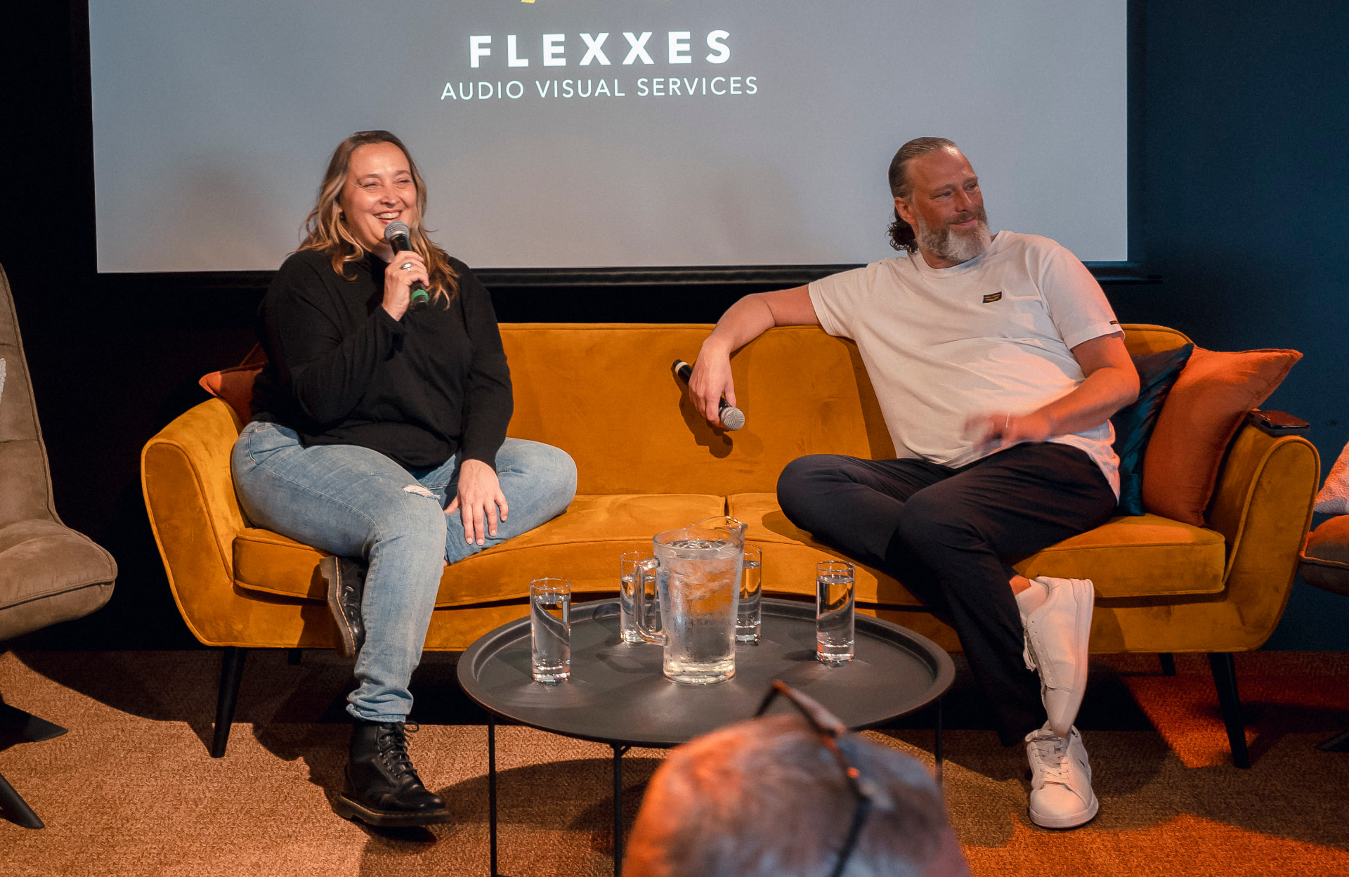 Two speakers in conversation on an orange sofa during the 2023 edition