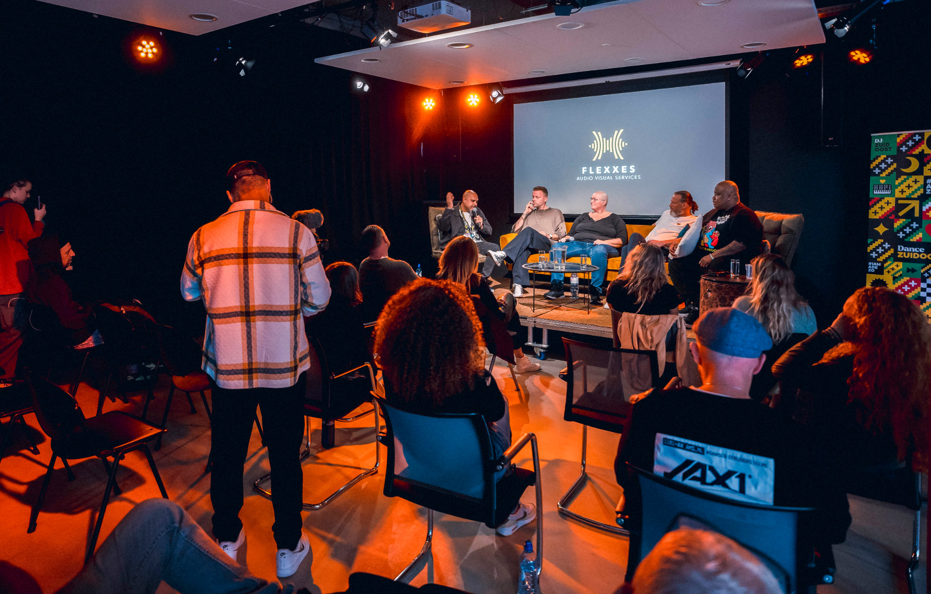 Wide view of the panel room with audience seated at The Extra Mile