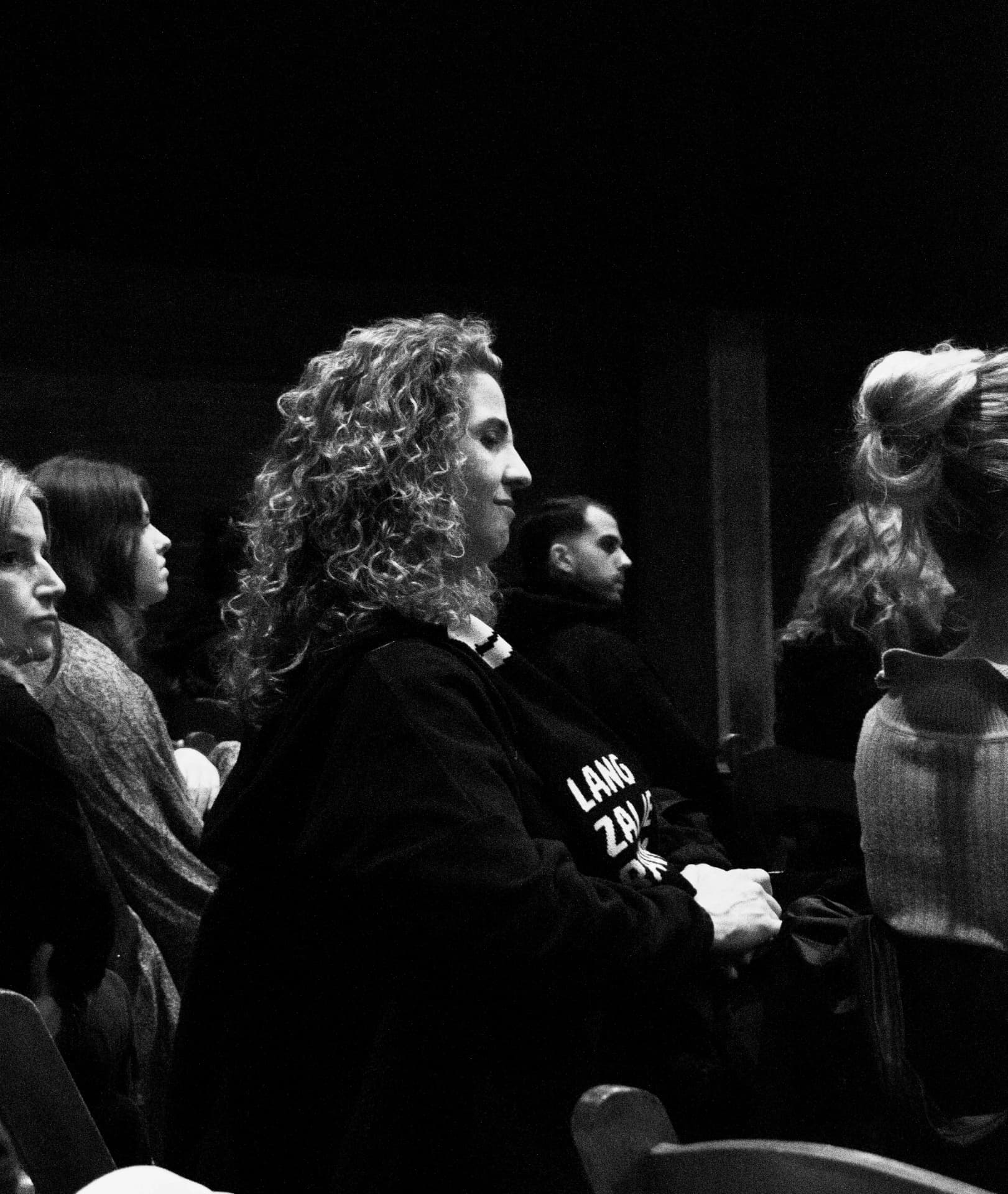 Attendee with curly hair listening attentively in black and white