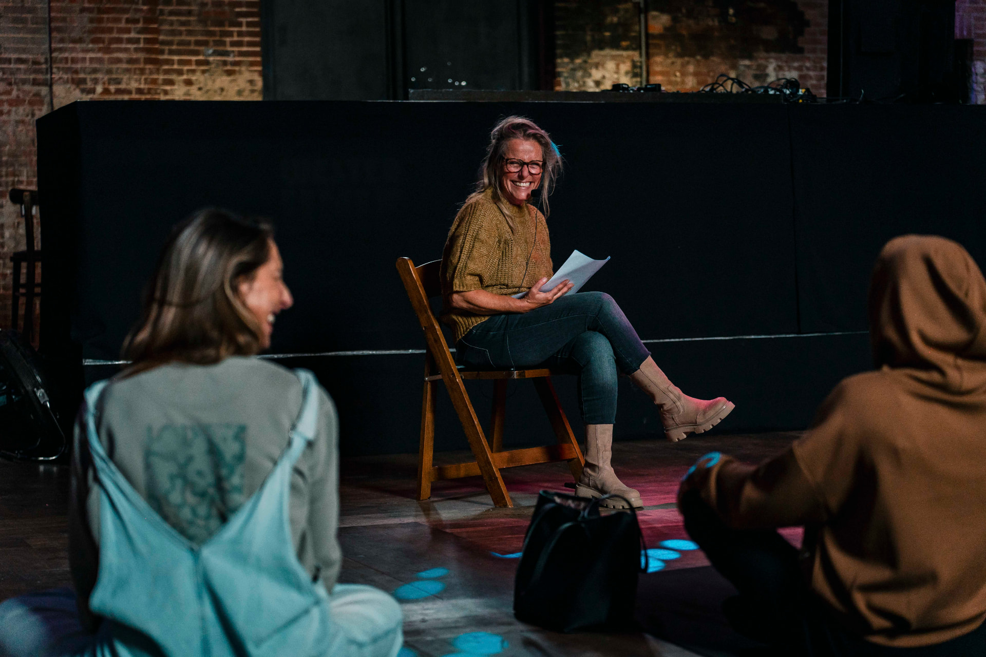 Smiling moderator seated on stage holding notes during the 2024 edition