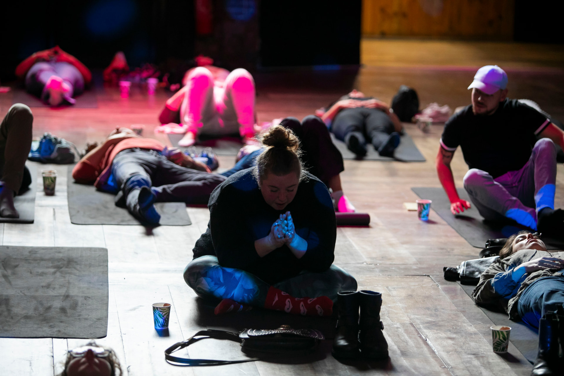 Audience members on mats during a guided wellness session in a darkened hall